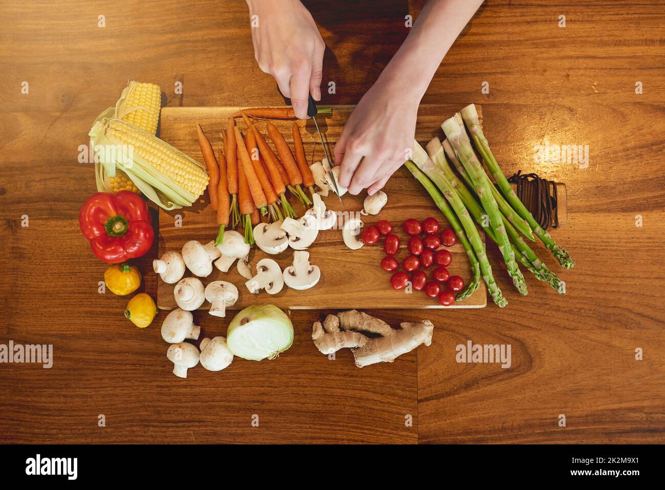 Manger vert, manger propre. Photo en grand angle d'une femme qui coupe une variété de légumes sains sur une planche à découper. Banque D'Images