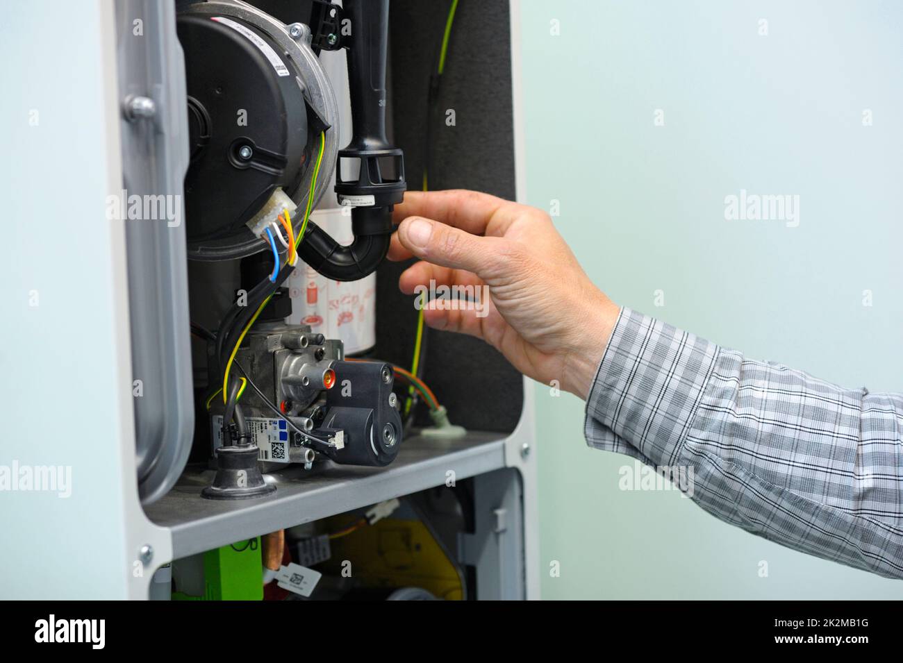 Homme travaillant main avec une chaudière à condensation de gaz démontée, pièces du condenseur de gaz de section. Banque D'Images