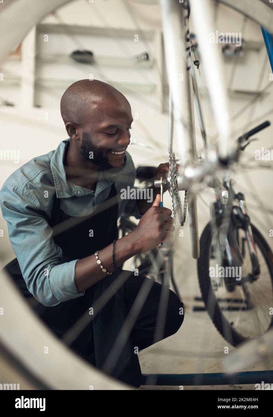 Pour que ce vélo soit tout neuf. Photo d'un beau jeune homme qui s'est accroupi seul dans son atelier et a réparé une roue de vélo. Banque D'Images