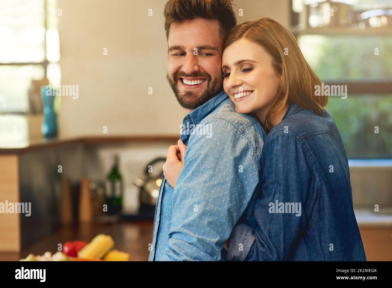 S'il cuisine pour vous, hes un gardien. Photo d'un jeune couple heureux partageant un moment affectueux dans la cuisine à la maison. Banque D'Images