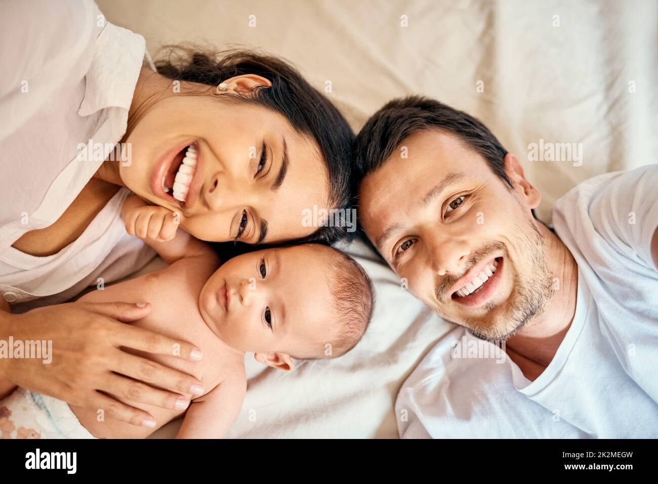 50 maman, 50 papa = 100 mignon. Photo en grand angle d'une mère et d'un père heureux prenant des selfies avec leur bébé garçon à la maison. Banque D'Images