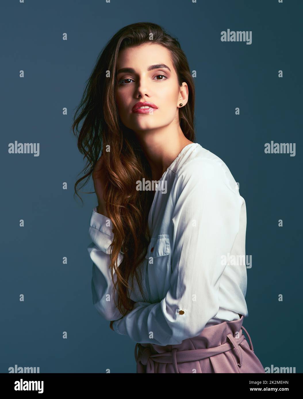 C'est tout sur la posture parfaite. Photo en studio d'une jeune femme à la mode, qui se pose sur un fond bleu. Banque D'Images