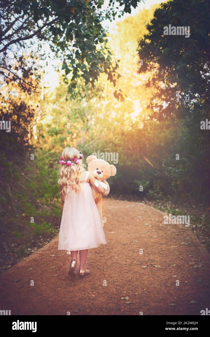 Je me demande où cela mène. Photo d'une petite fille méconnaissable marchant avec son ours en peluche au milieu d'une route de terre. Banque D'Images