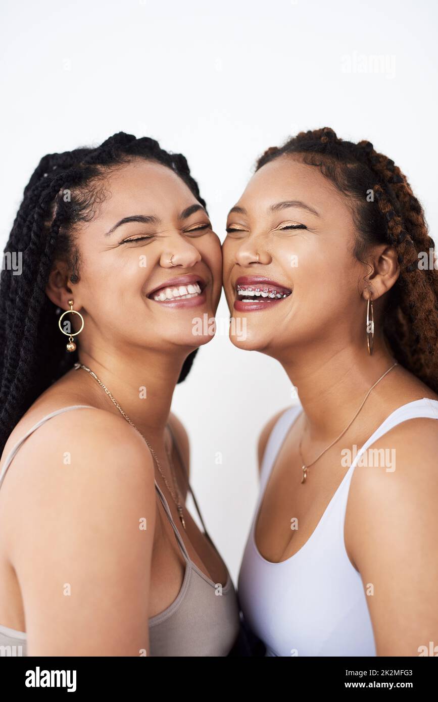 Le rire est beau. Photo de studio de deux jeunes femmes qui se posent sur un fond gris. Banque D'Images