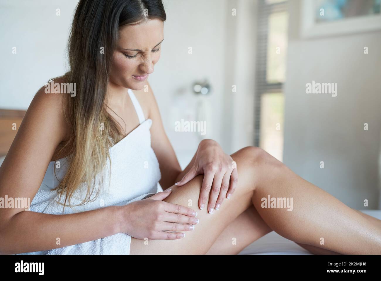 C'est la cellulite que je vois. Photo d'une jeune femme qui ne regarde pas impressionnée en pinçant la peau sur sa cuisse dans sa chambre à la maison. Banque D'Images