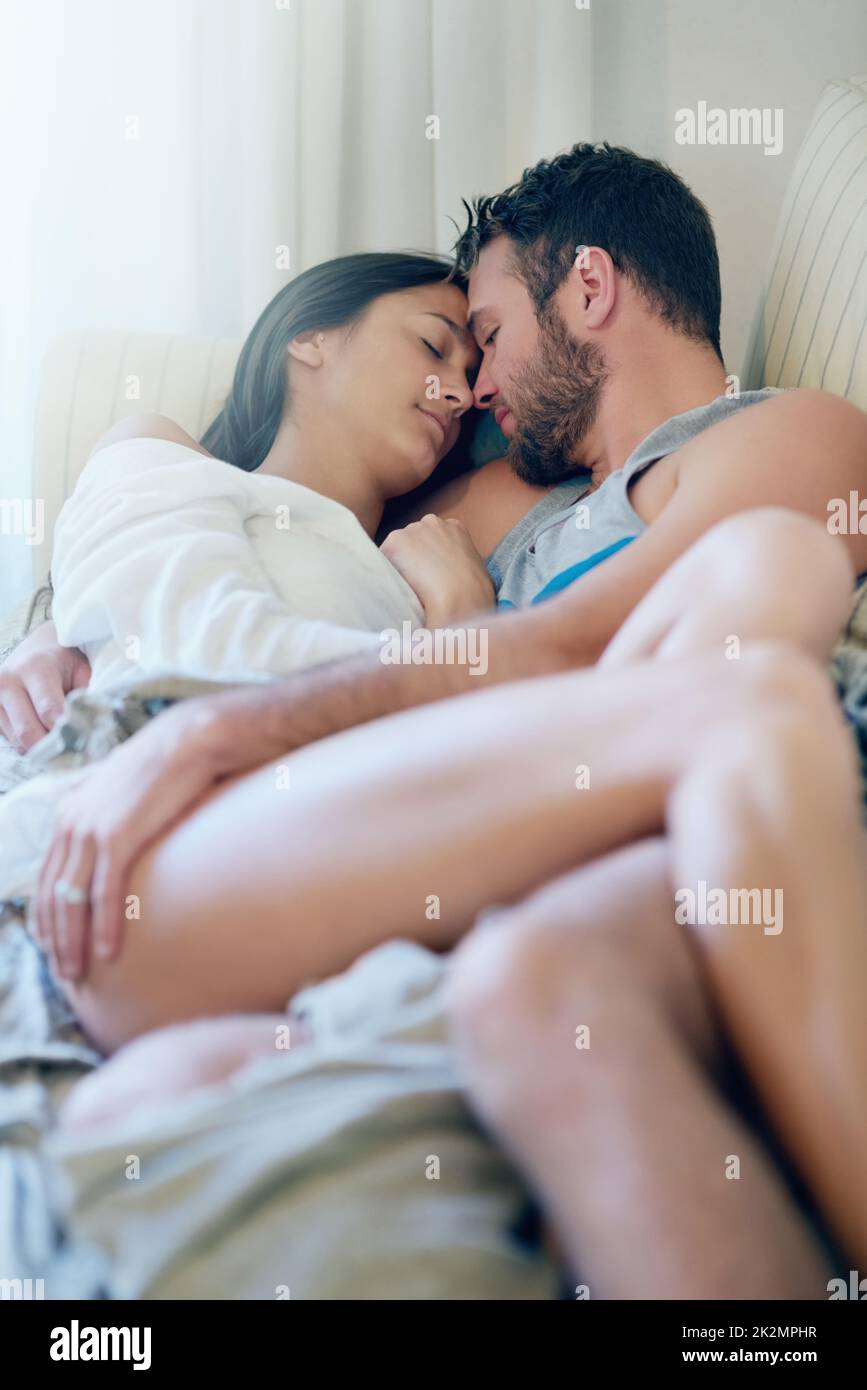 Sans danger les uns dans les autres bras. Photo d'un jeune couple en profitant d'un moment romantique sur le canapé le matin. Banque D'Images
