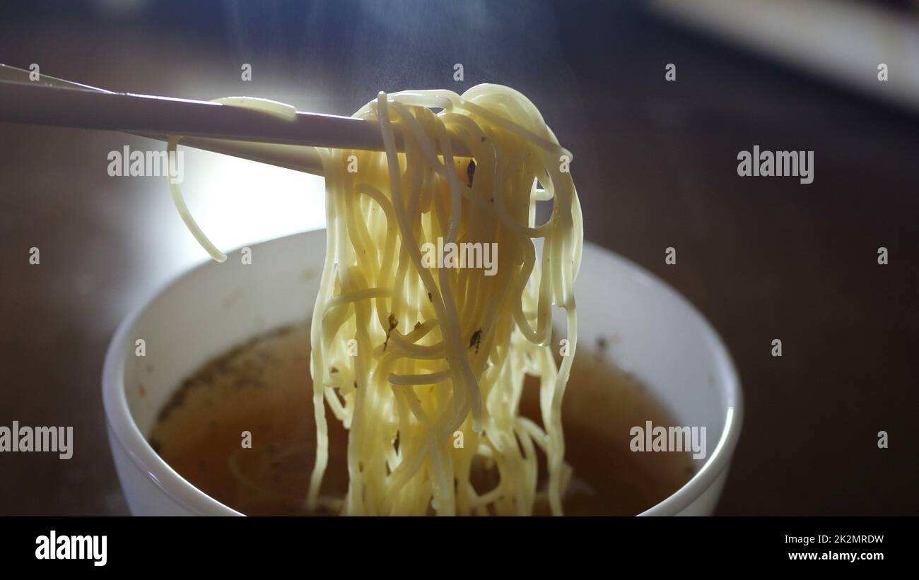 Gros plan de nouilles ramen jaune instantané et de baguettes chinoises Banque D'Images