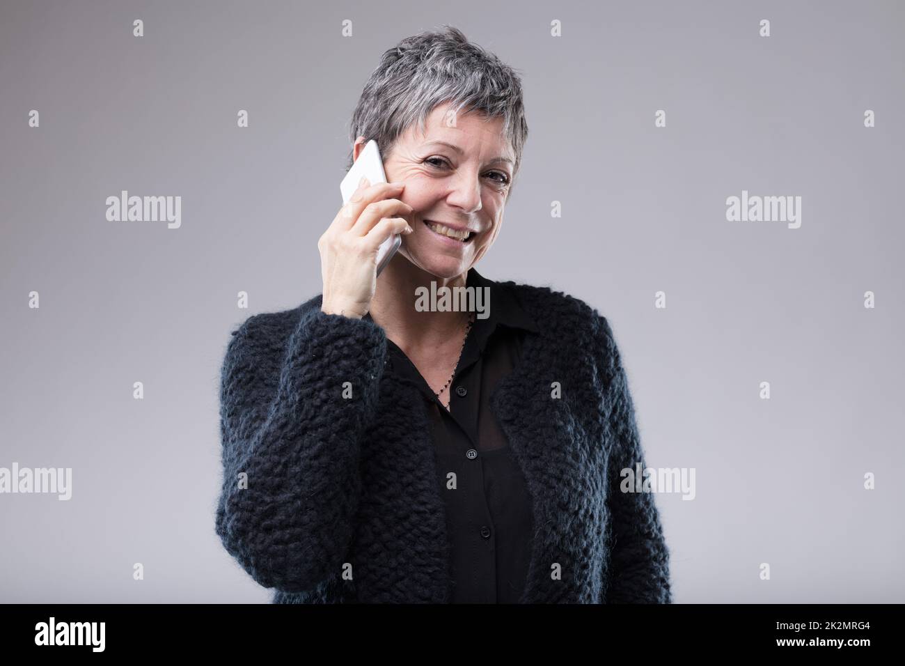 Femme souriante et confiante discutant sur son mobile Banque D'Images