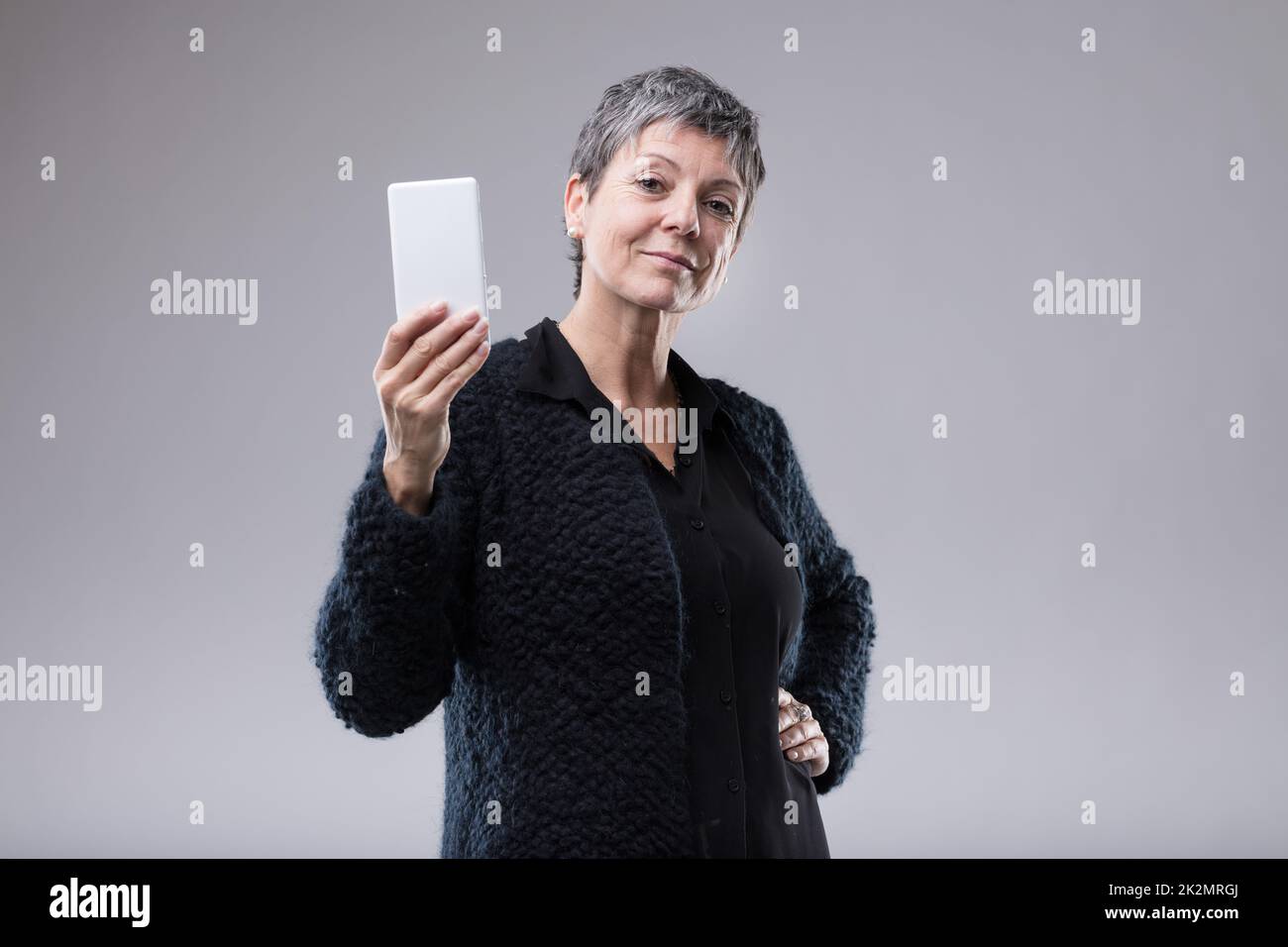 Une femme attirante et sûre d'elle-même qui tient un mobile Banque D'Images
