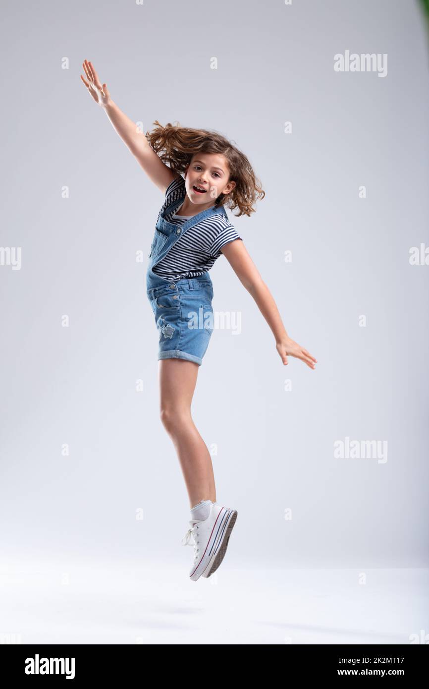 Jeune fille sautant dans l'air avec les bras étendus Banque D'Images