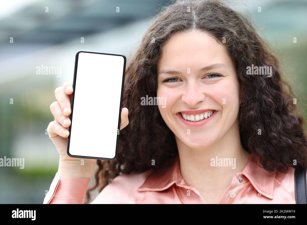 Une femme heureuse avec un chemisier montrant un écran de téléphone vierge Banque D'Images