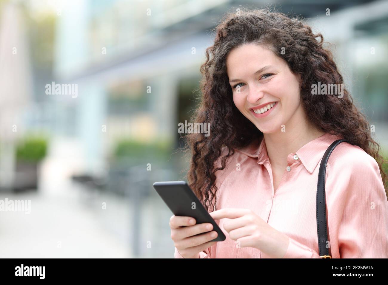 Une femme heureuse vous regarde en tenant votre téléphone portable Banque D'Images