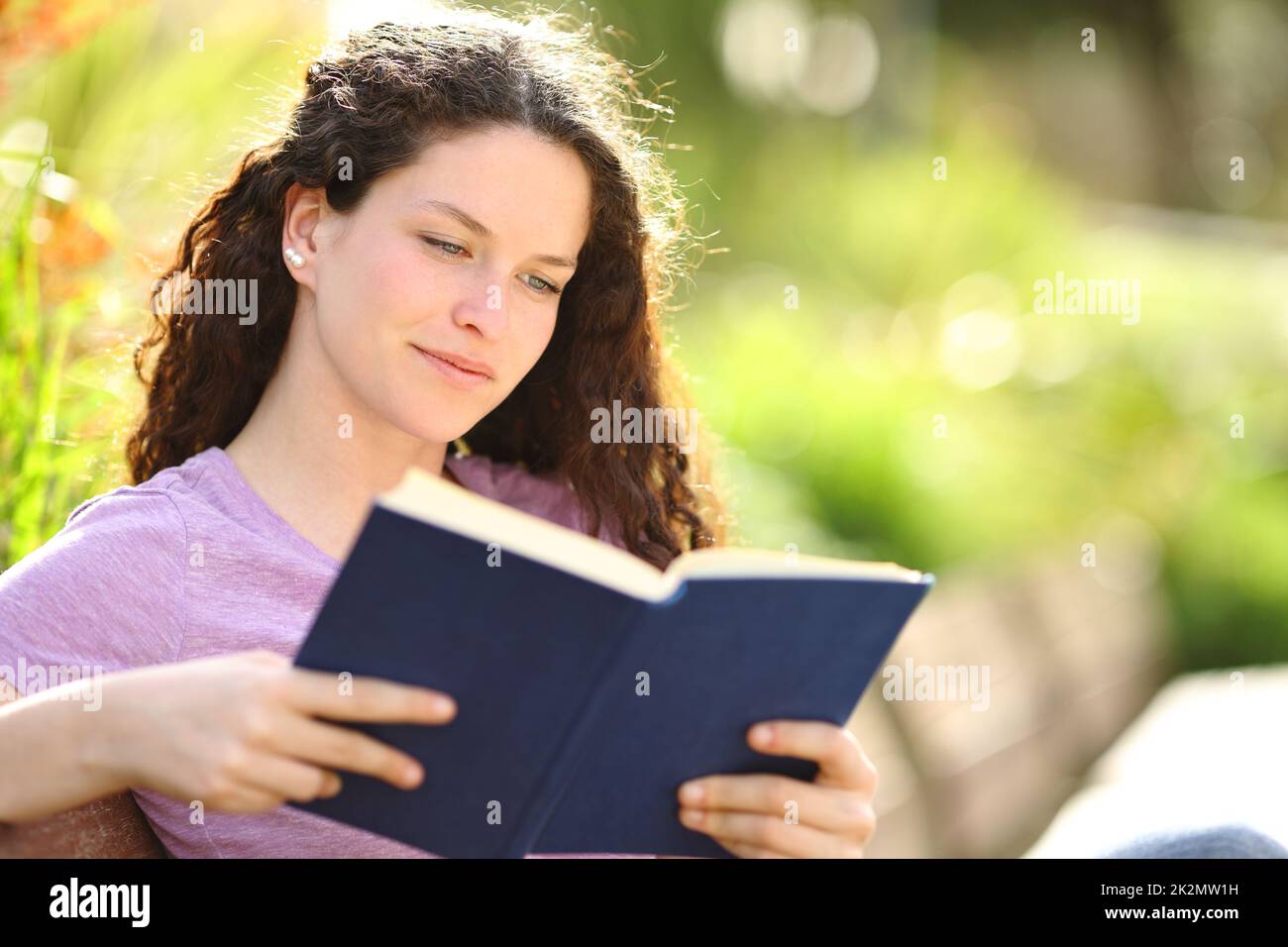 Femme détendue lisant un livre dans un beau parc Banque D'Images