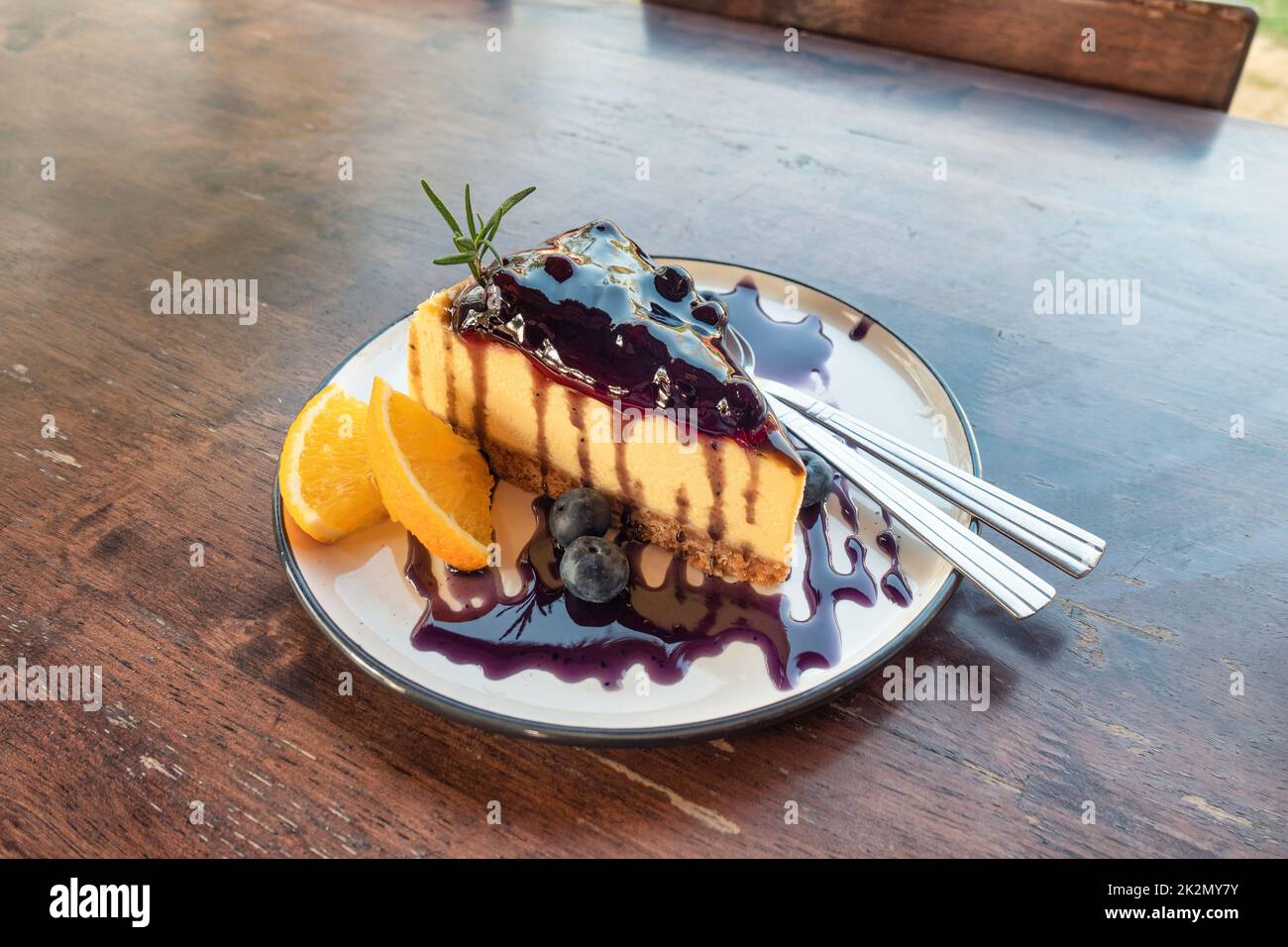 Cheesecake aux myrtilles avec biscuit, confiture et orange dans le plat sur la table Banque D'Images