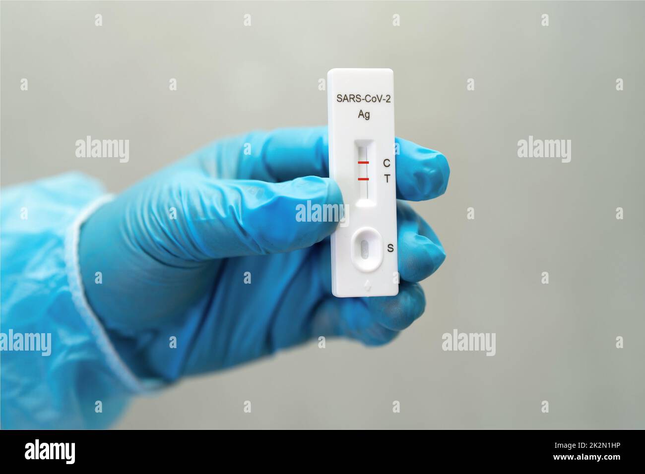 Un médecin asiatique en costume d'EPI montre un résultat de test positif avec de la salive A. Banque D'Images