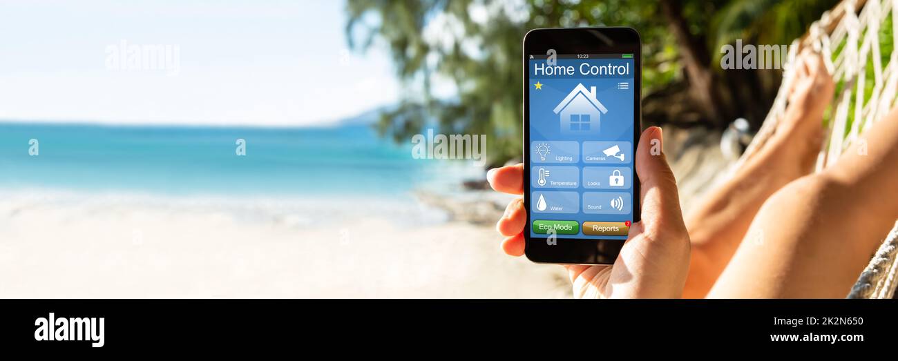 Femme utilisant Smart Home sur un téléphone portable à Beach Banque D'Images