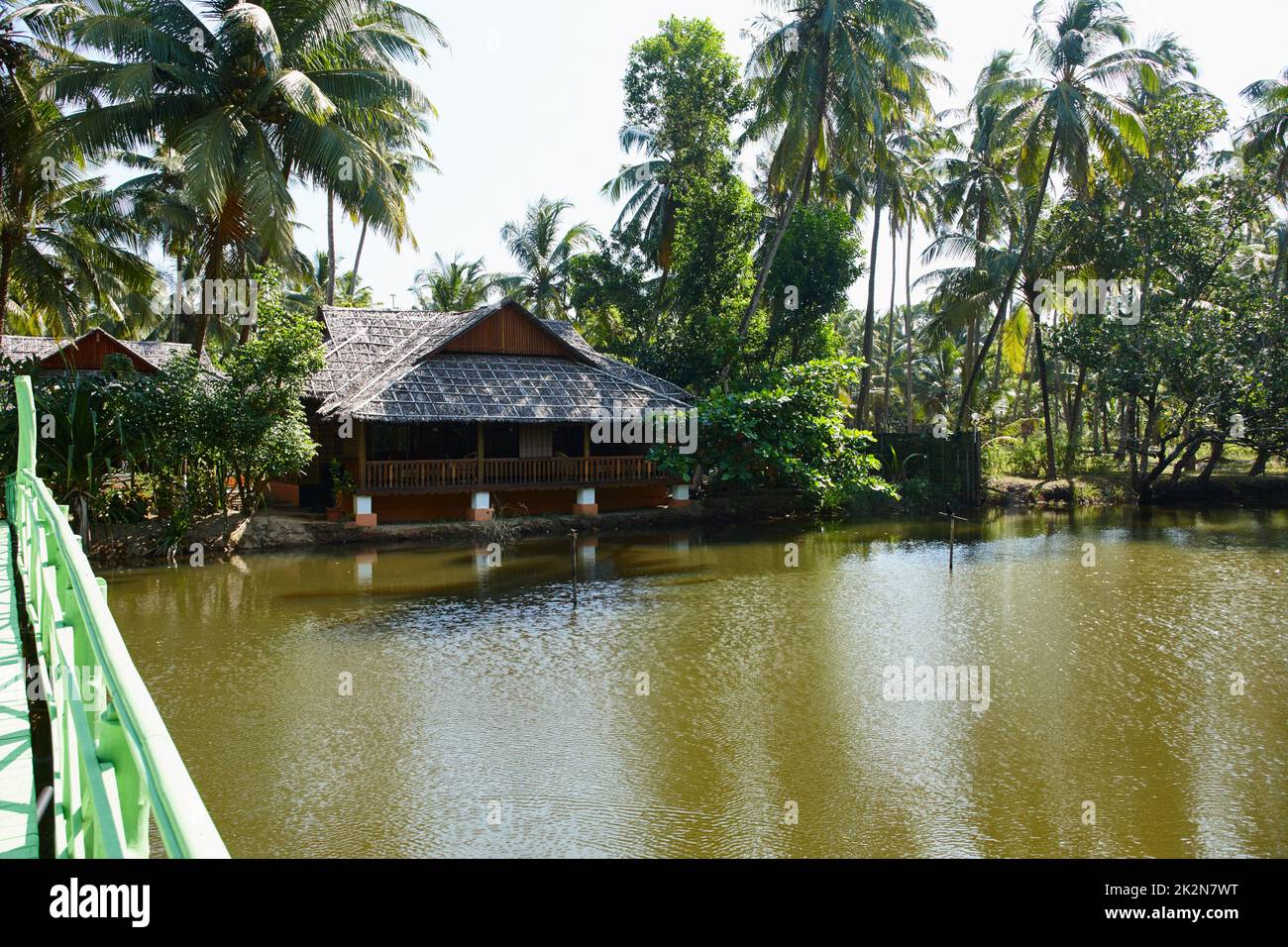 Tranquillité idyllique. Bâtiment traditionnel en bois entouré de palmiers tropicaux sur les rives d'une rivière en Inde. Banque D'Images