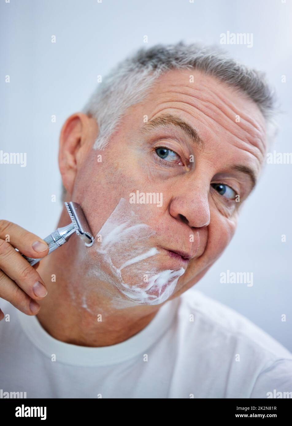 Je dois me concentrer lors du rasage. Photo d'un homme mûr se rasant le visage dans une salle de bain à la maison. Banque D'Images