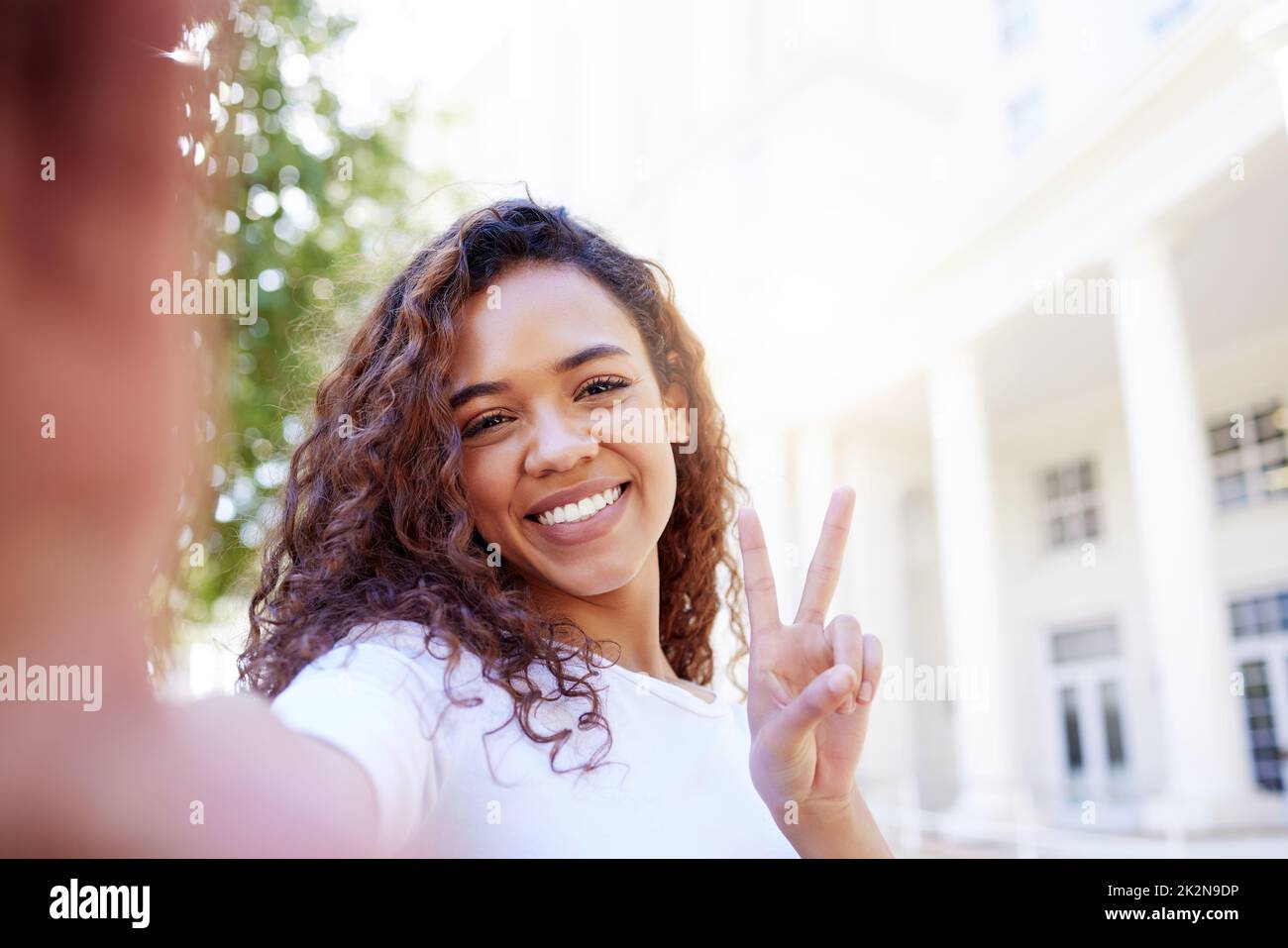 Il n'y a pas de chemin vers le bonheur le bonheur est le chemin. Photo d'une femme montrant un geste de paix tout en prenant un selfie à l'extérieur. Banque D'Images