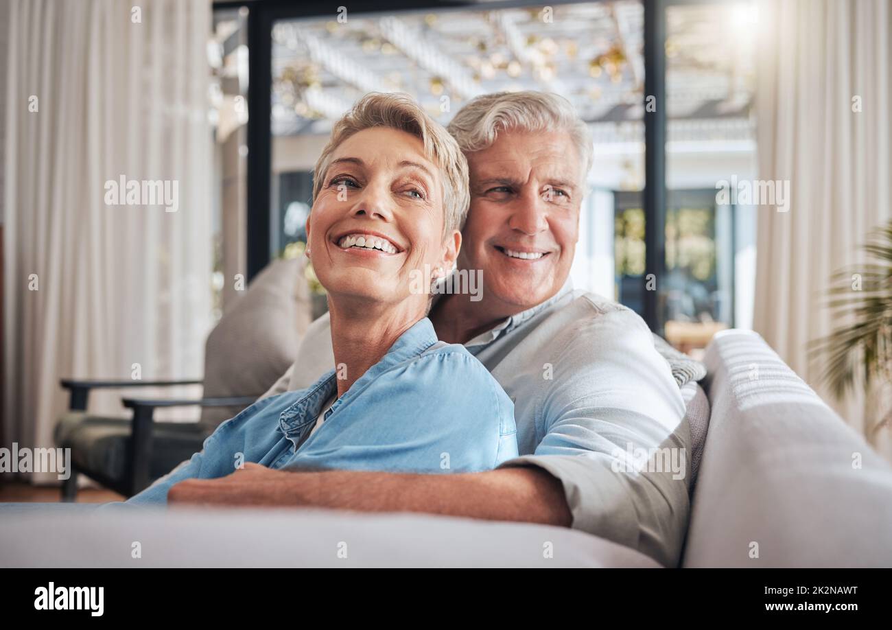 L'amour, le couple et la retraite avec une femme et un homme âgés sur un canapé pour se détendre dans leur maison ensemble. Heureux, sourire et penser avec un homme âgé et Banque D'Images