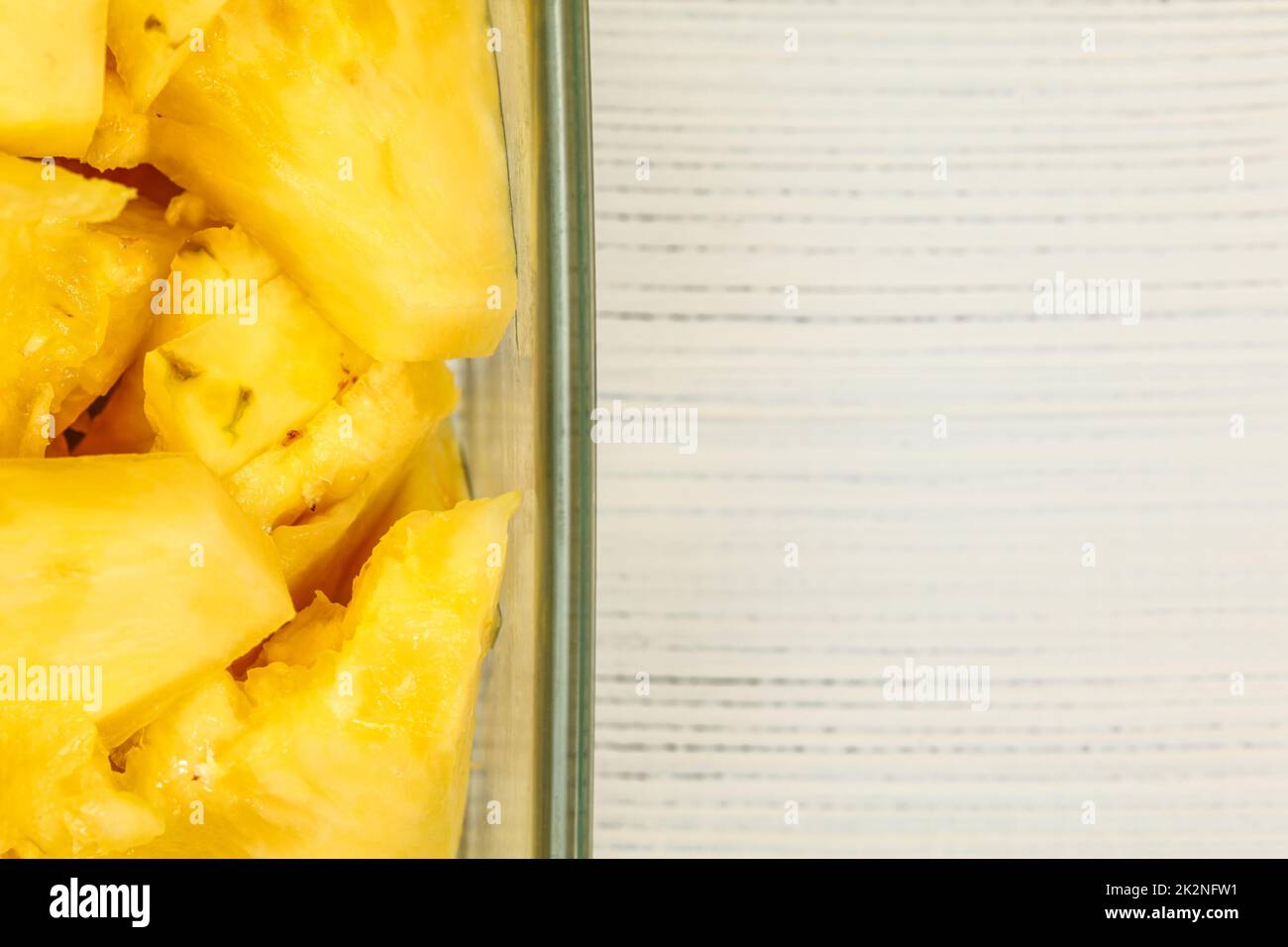 Vue sur table, détail - jaune ananas, en morceaux, dans un bol en verre carré, tableaux blancs 24 / espace pour le texte sur la droite. Banque D'Images