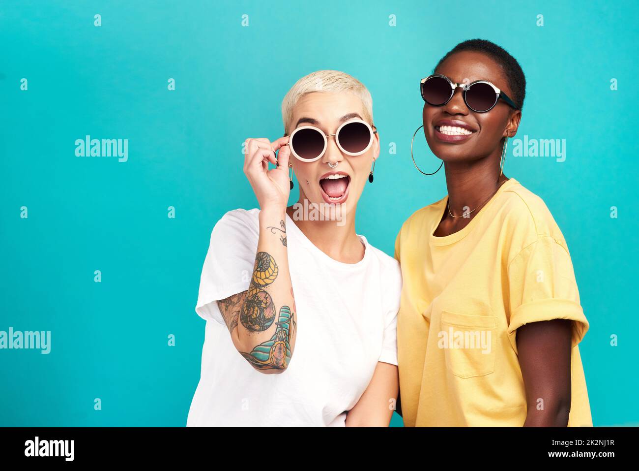 L'avenir est prometteur.Photo de studio de deux jeunes femmes portant des lunettes de soleil sur fond turquoise. Banque D'Images