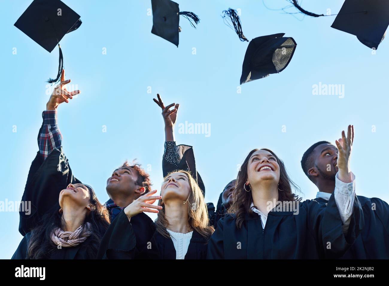 Nous l'avons fait. Photo d'un groupe d'élèves qui lançaient leur chapeau dans les airs le jour de la remise des diplômes. Banque D'Images