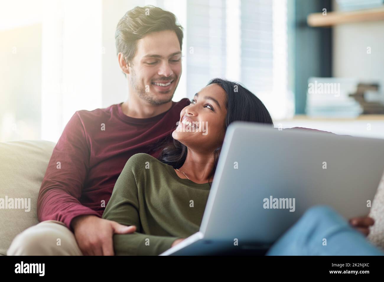 Je pense que c'est prêt à être affiché. Photo d'un jeune couple affectueux utilisant son ordinateur portable tout en étant assis sur le canapé à la maison. Banque D'Images