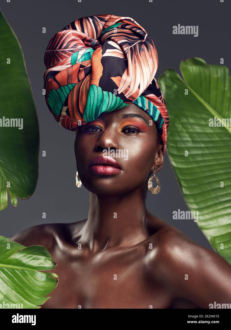 Plus que du tissu, sa ma couronne. Photo studio d'une belle jeune femme portant une tête d'enveloppement africaine traditionnelle sur un fond verdoyant. Banque D'Images