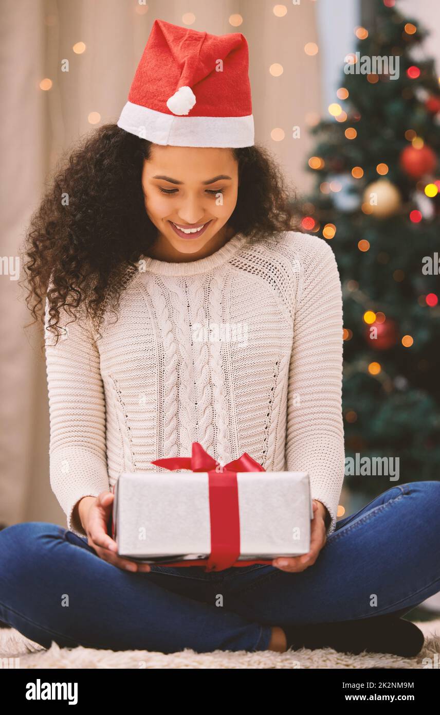 Laissez le cadeau de Noël remplir votre coeur de bonheur. Photo d'une jeune femme heureuse ouvrant des cadeaux pendant Noël à la maison. Banque D'Images