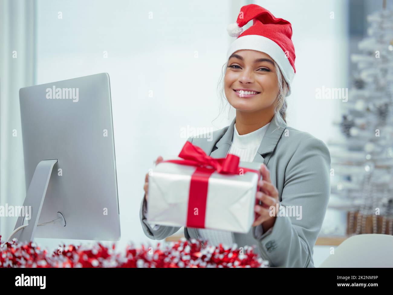 Noël soigneusement emballé. Portrait d'une jeune belle femme qui répande la joie de Noël avec des cadeaux au bureau. Banque D'Images