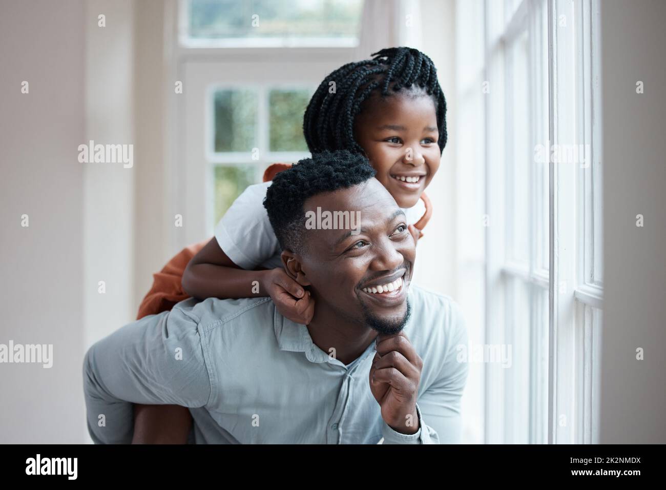 Elle voit le monde d'une autre manière avec son père. Photo d'un père donnant à sa fille une promenade en porcgyback à la maison. Banque D'Images