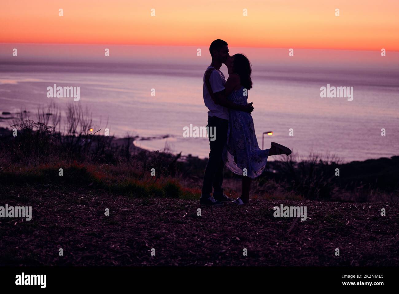 Fou d'amour. Prise de vue en longueur d'un jeune couple affectueux et silhoueté au coucher du soleil. Banque D'Images