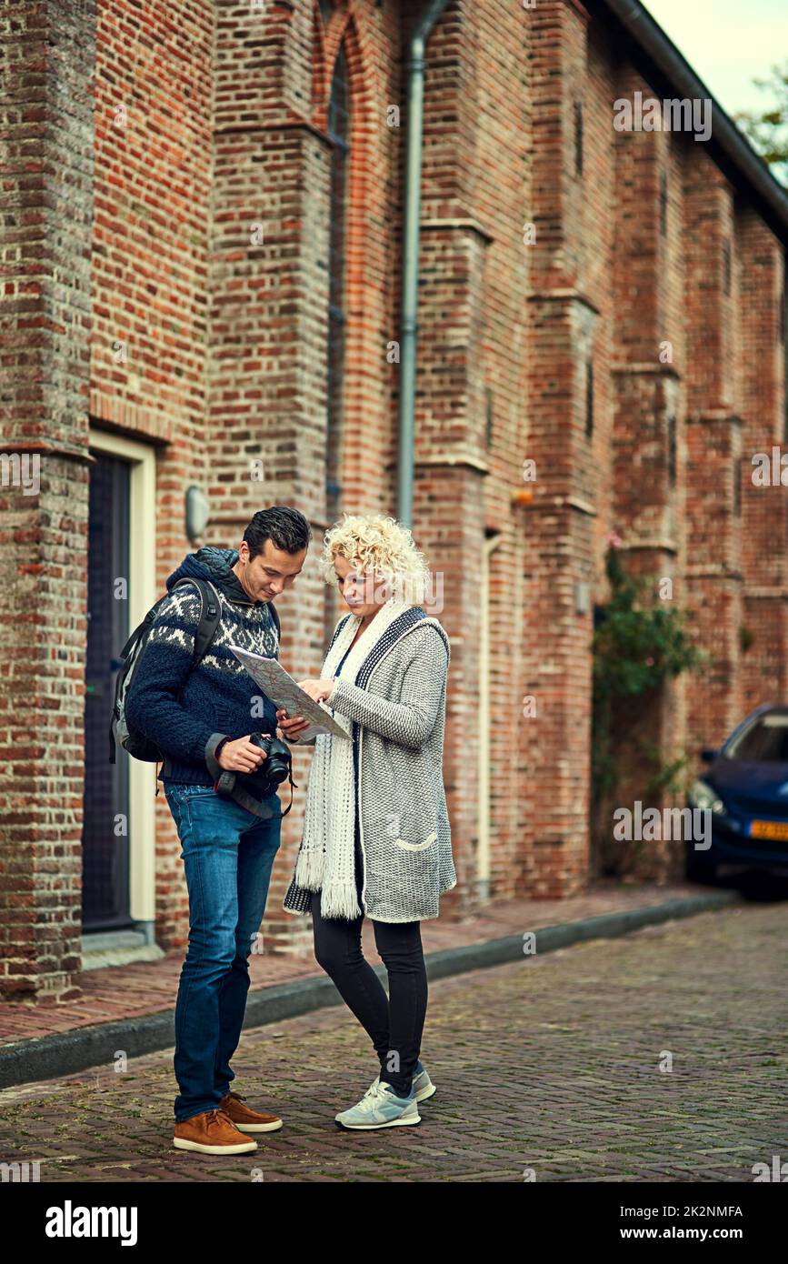 Voyons où nous en sommes Prise de vue en longueur d'un jeune couple regardant une carte pendant ses vacances. Banque D'Images