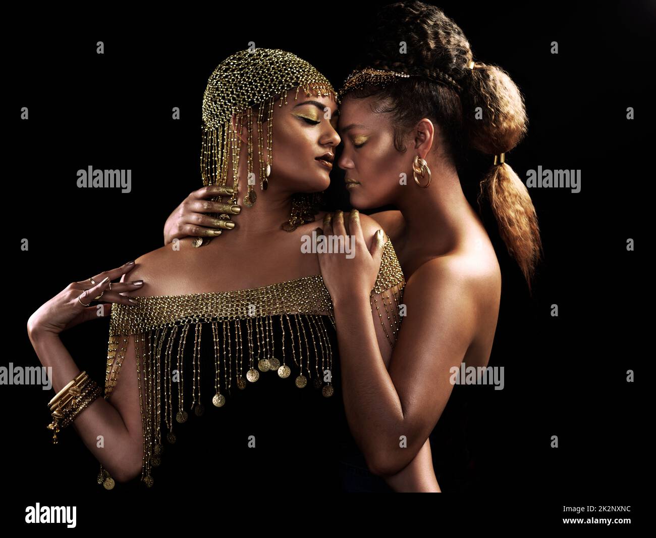 Chaque femme est une reine. Photo courte de deux jeunes femmes élégantes et habillées se posant ensemble sur un arrière-plan sombre. Banque D'Images