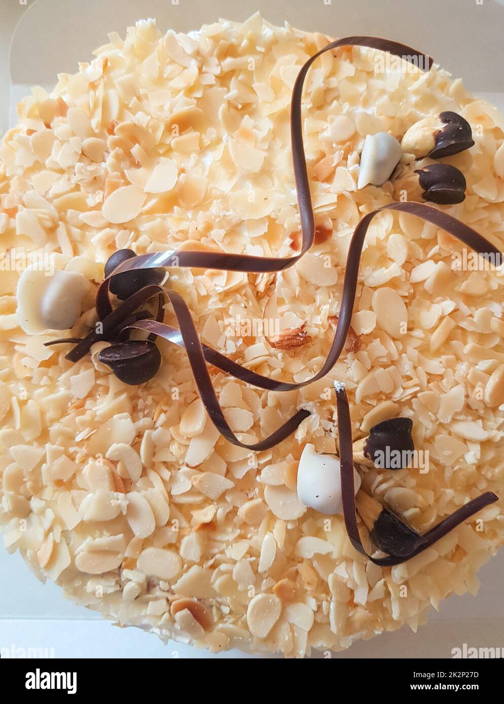 Un gâteau aux amandes rond entier décoré de rayures au chocolat et de noix. Mets sucrés. Dessert sucré. La nourriture. Gros plan Banque D'Images