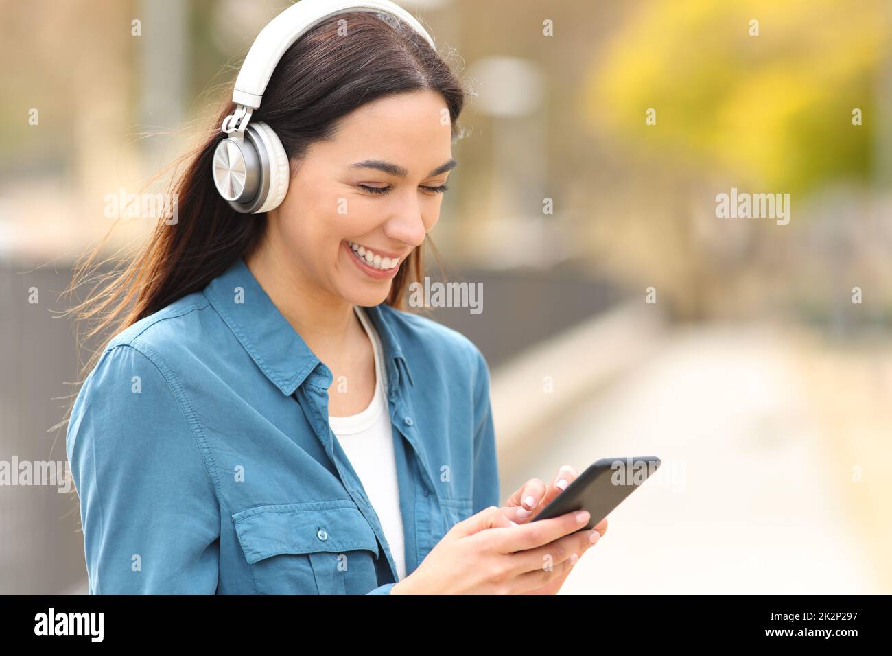 Une femme heureuse écoute de la musique ou regarde des médias sur son téléphone Banque D'Images