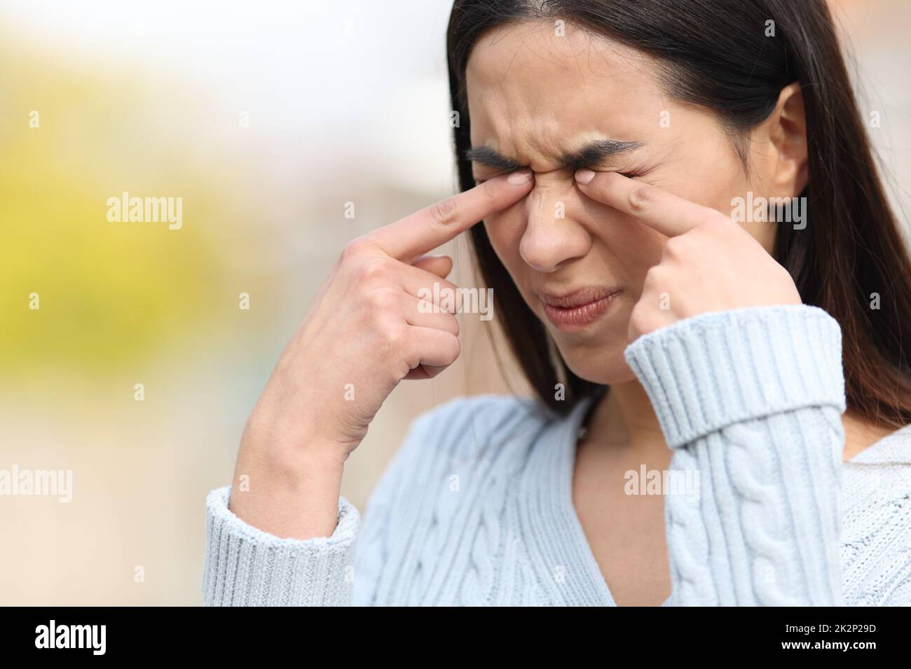 Une femme se grattant les yeux avec ses mains dans un parc Banque D'Images