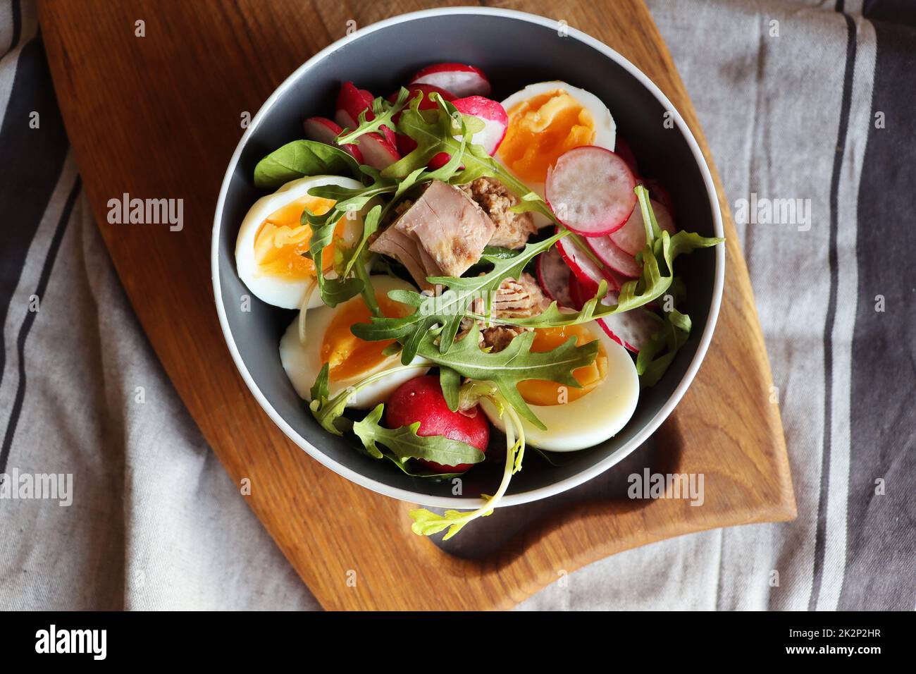 Salade fraîche avec thon, radis, œufs, arugula d sur fond gris vue de dessus. Une alimentation saine. Salade de printemps Banque D'Images