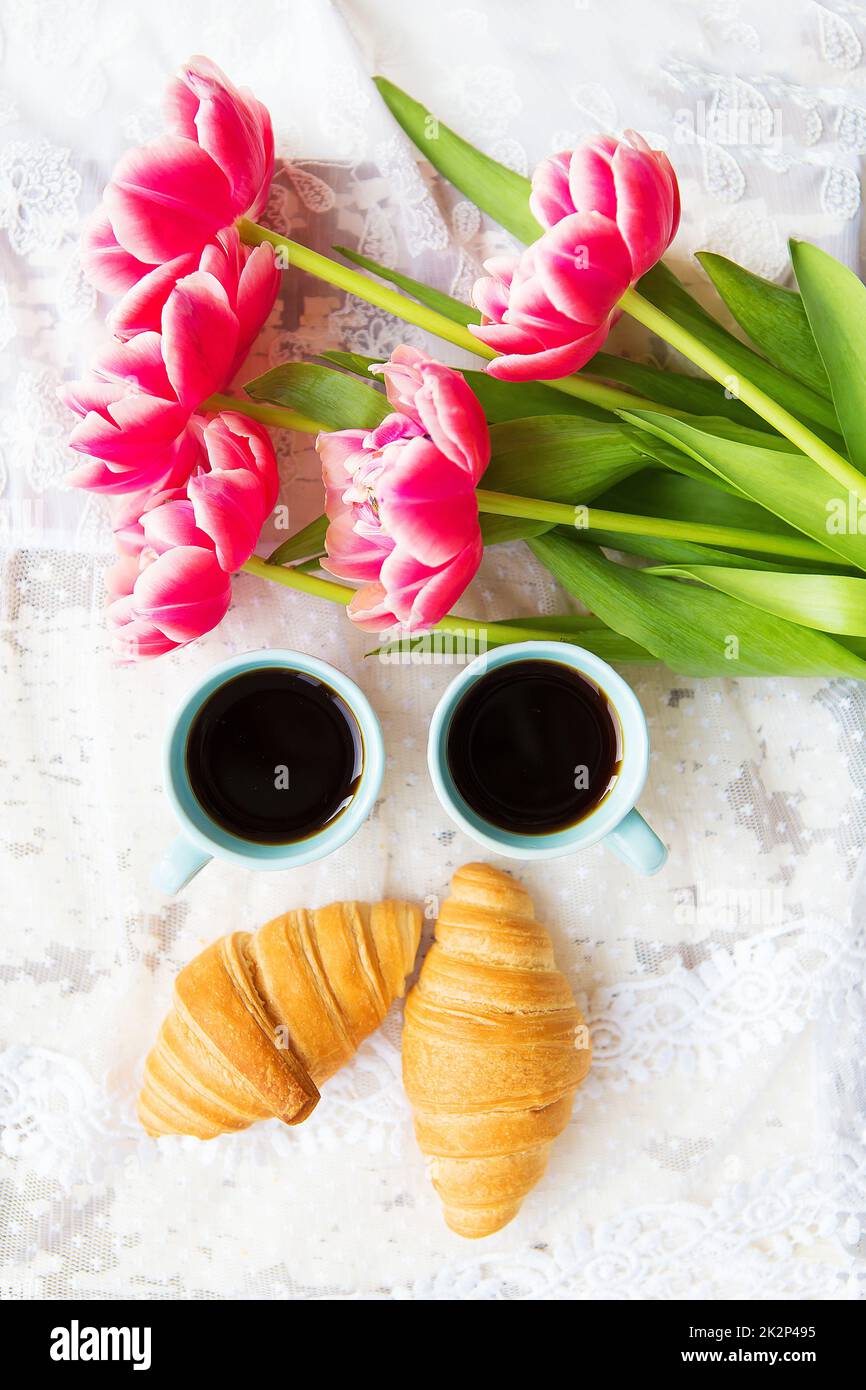 une bonne tasse de café, des croissants et des tulipes roses sur une vieille table blanche, en gros plan Banque D'Images