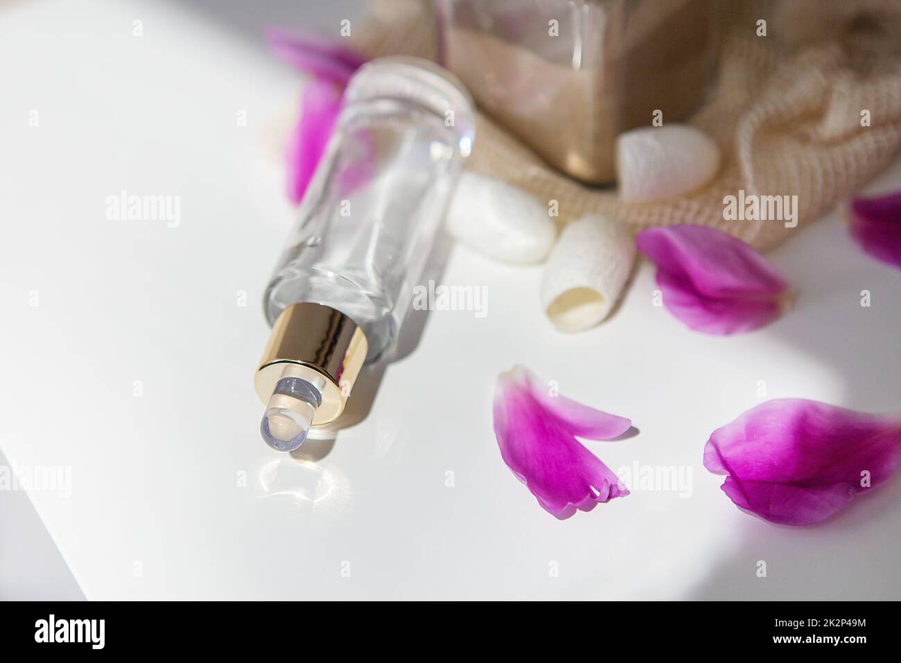 Cosmétiques naturels, un beau pot de liquide pour le visage sur le fond des pétales roses des pivoines. Banque D'Images