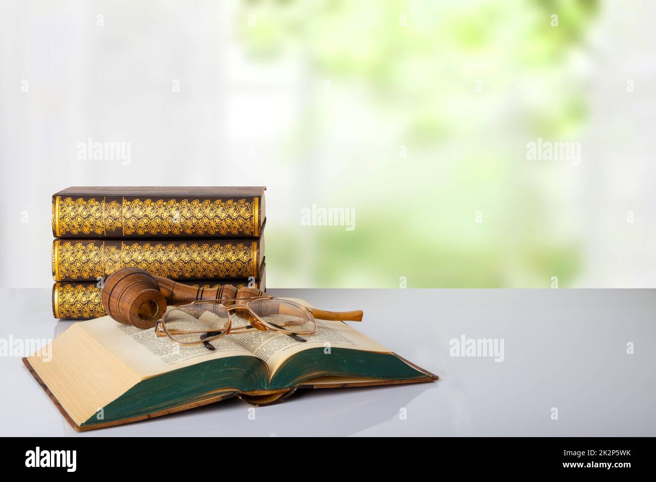 Gros plan d'un livre antique avec un tuyau de tabac sur eux et une paire de lunettes et une pile de trois livres devant un fond lumineux. La journée des enseignants. Retour à l'école. Espace. Banque D'Images