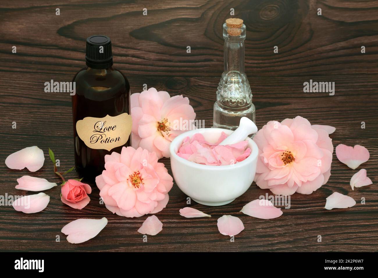 Fleurs roses pour la potion magique d'amour sort avec concoction dans une bouteille, cristal de quartz rose et eau de source. Wiccan occulte concept mystique pour l'amant Banque D'Images