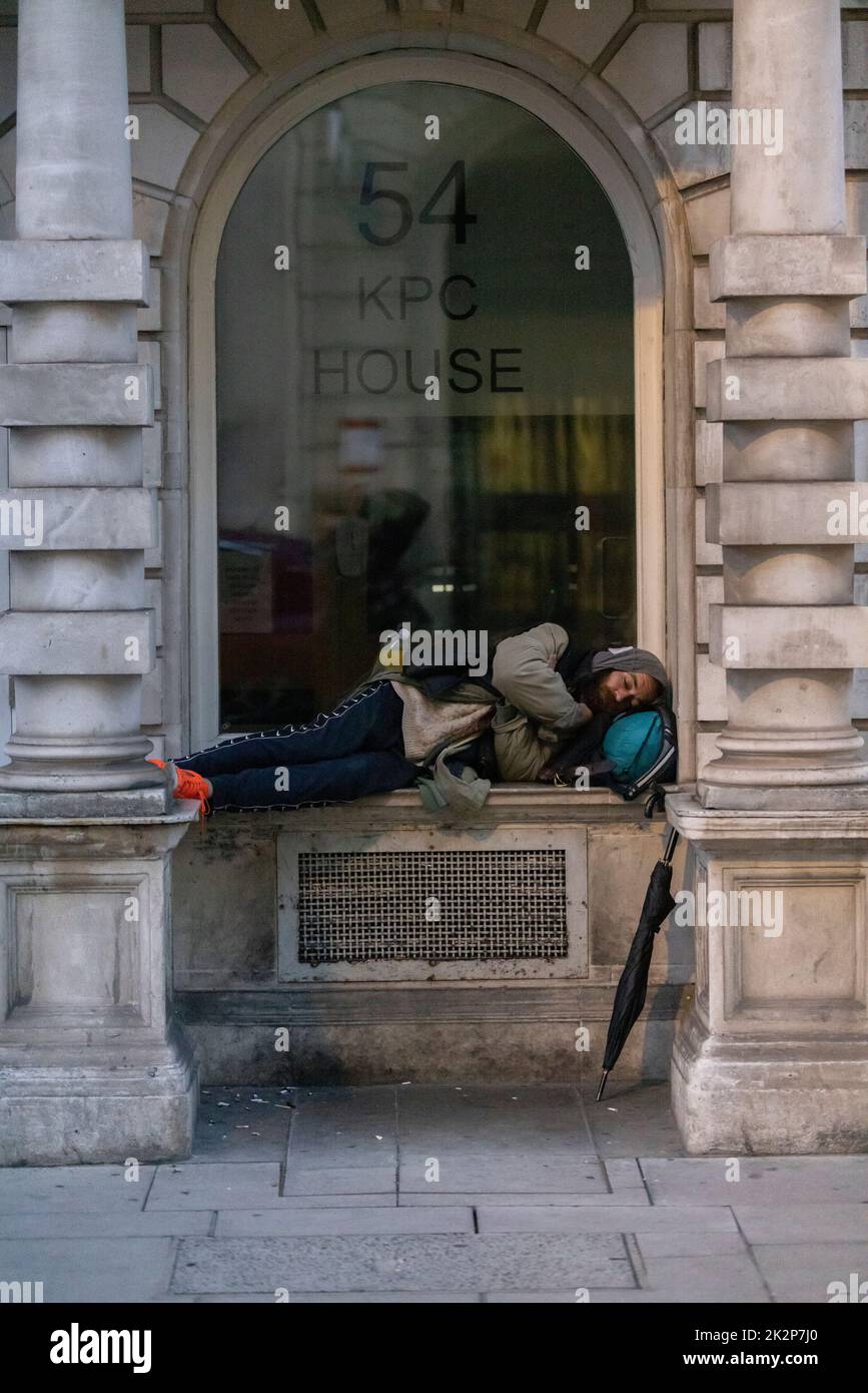 Un homme sans-abri dort perché sur une bordure de fenêtre sur Pall Mall, l'une des rues les plus exclusives de Londres, Angleterre, Royaume-Uni Banque D'Images