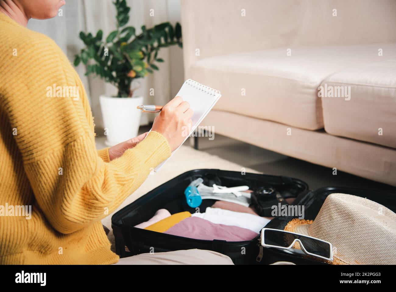 Femme papier d'écriture prendre note et d'emballage de la valise à papier d'écriture de vacances liste assis sur la chambre Banque D'Images