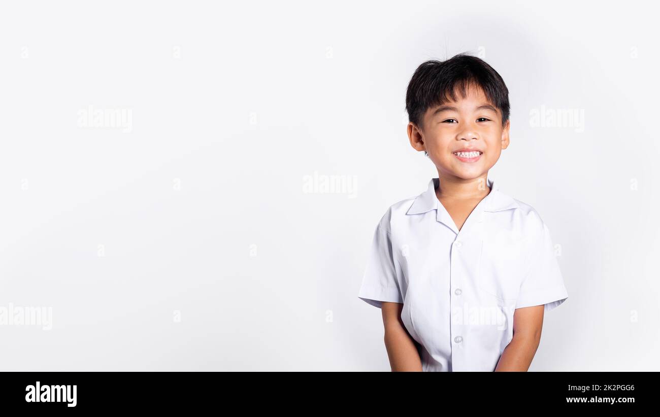Asiatique adorable tout-petit souriant heureux portant l'uniforme thaï étudiant debout Banque D'Images