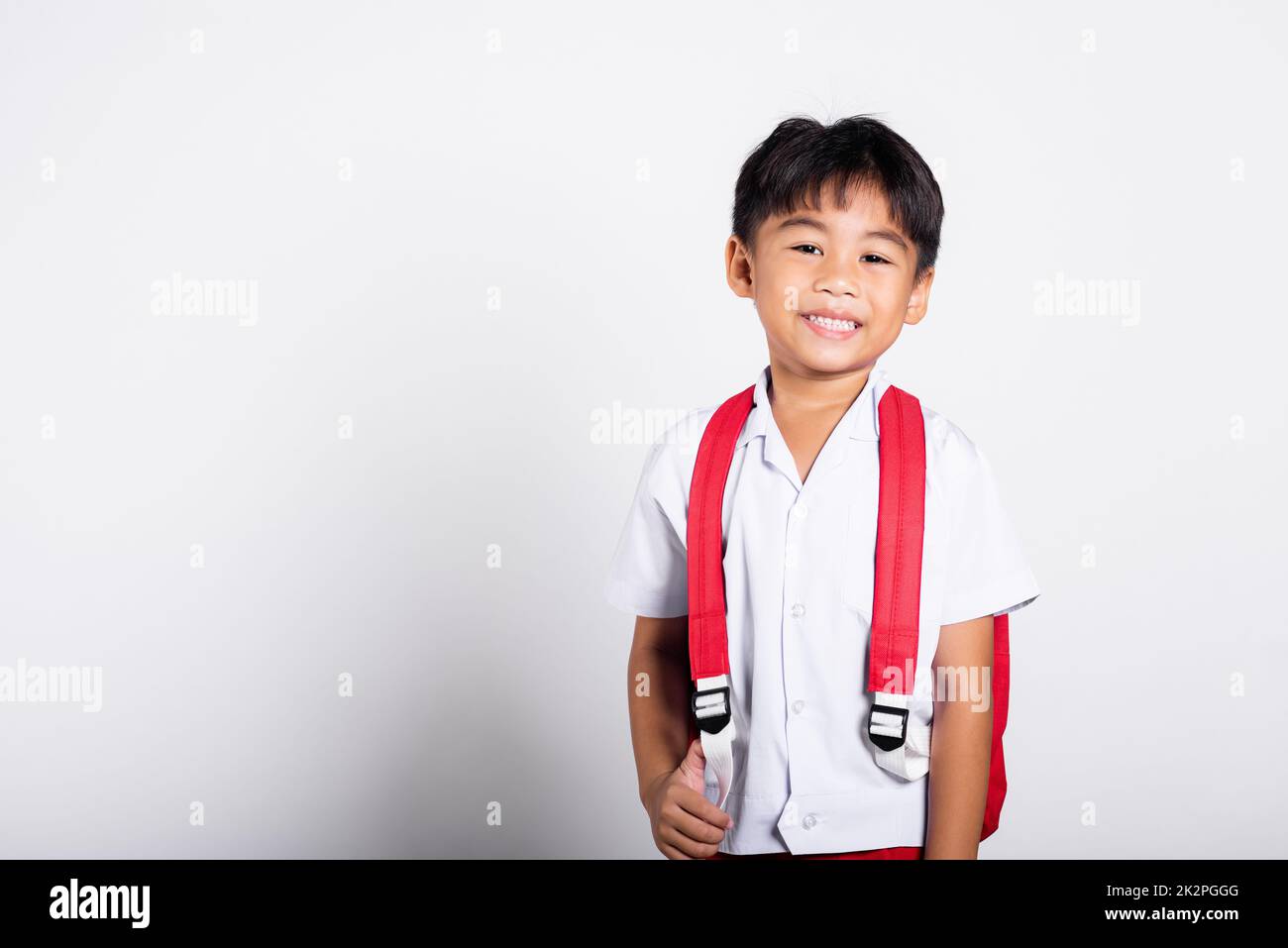 Asiatique adorable tout-petit souriant heureux portant l'uniforme thaï étudiant debout Banque D'Images