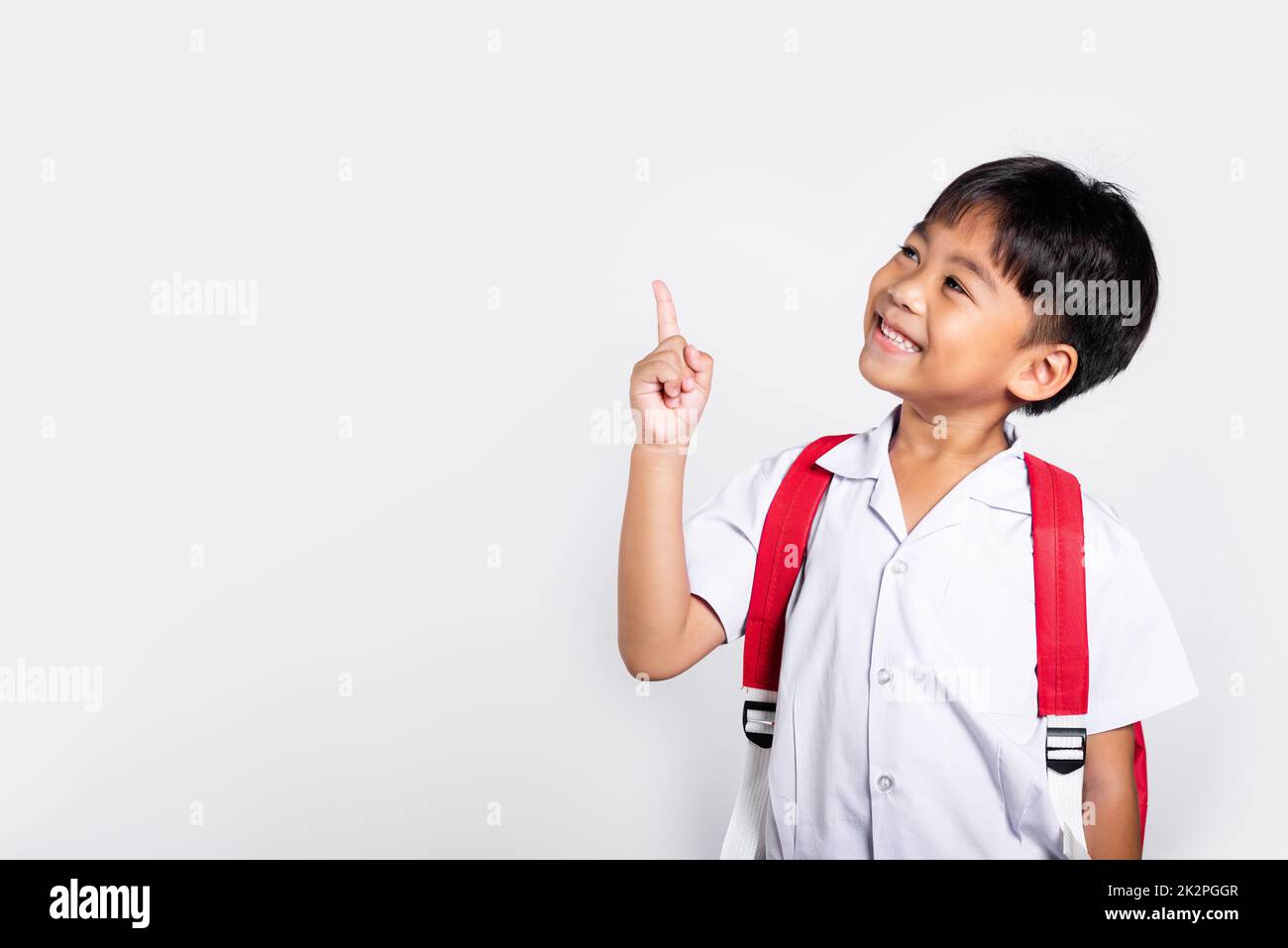 Asiatique tout-petit sourire Happy Wear étudiant thaïlandais uniforme pantalon rouge continue de pointer le doigt sur l'espace de copie Banque D'Images