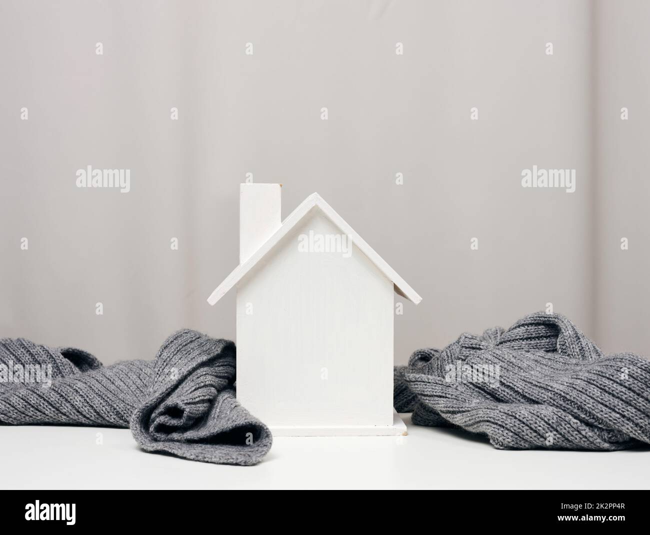maison miniature en bois blanc enveloppée d'une écharpe tricotée grise.Concept d'isolation de bâtiment, prêts pour réparations Banque D'Images