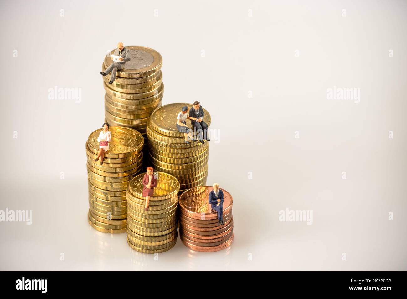 Divers hommes d'affaires assis sur des piles de pièces d'argent. Banque D'Images